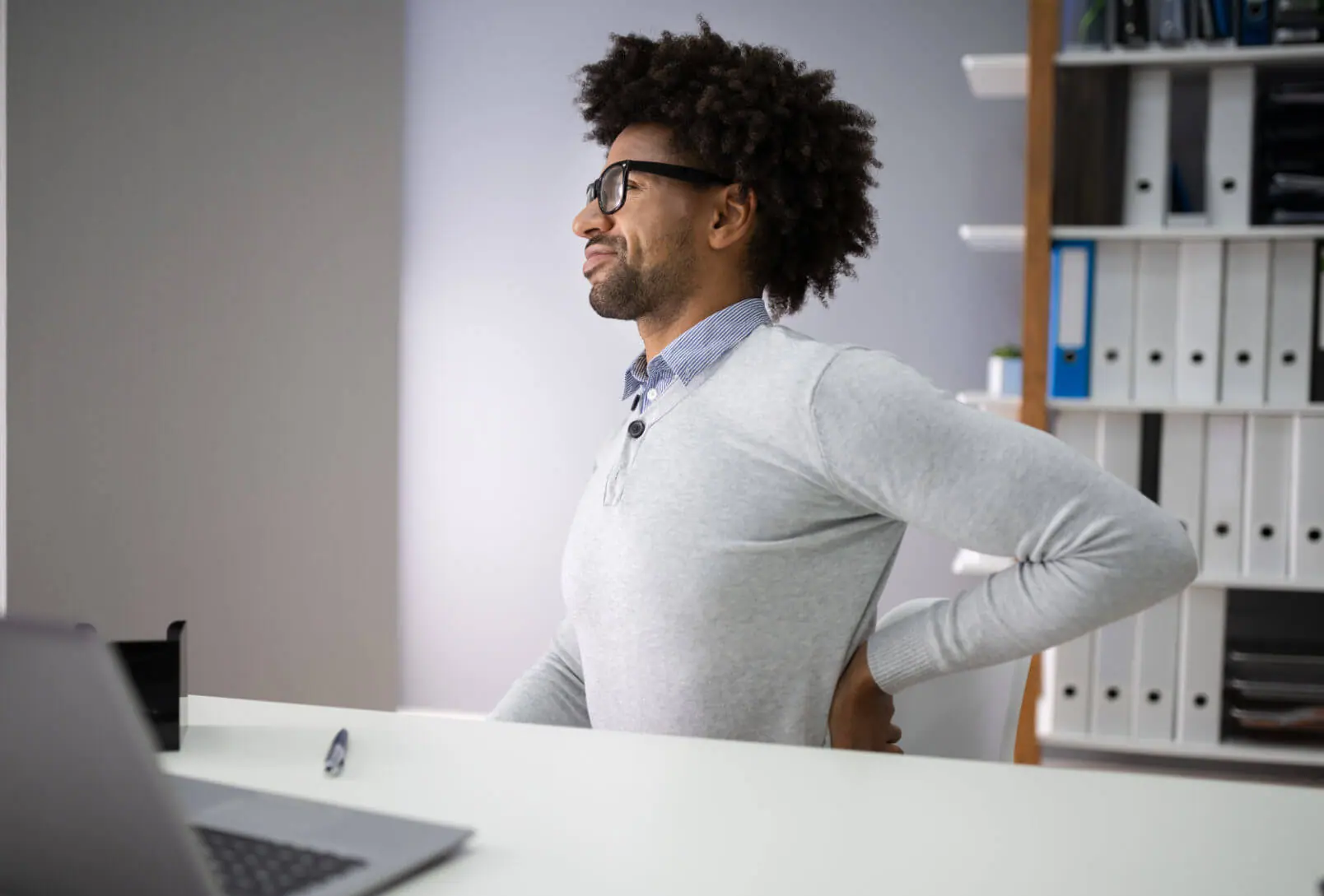 man feeling pain in lower back from sitting at a desk